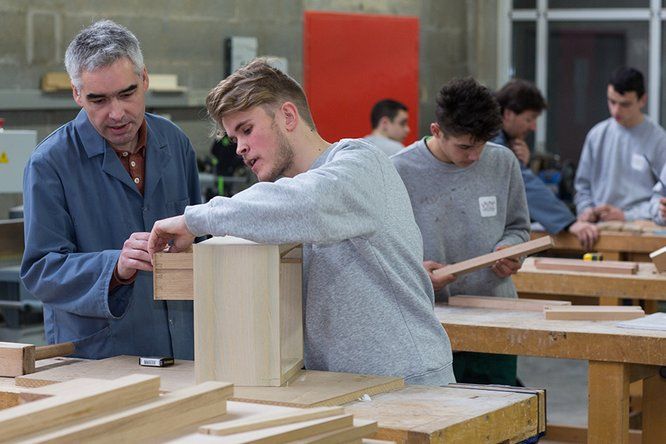 Apprenti avec formateur métier du bois à l'atelier