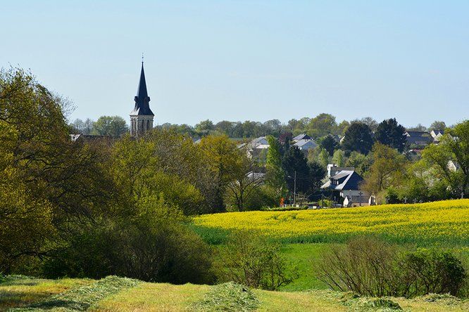 des champs et au loin un bourg avec un clocher et quelques habitations