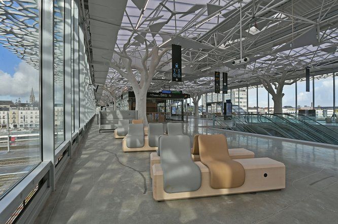 Vue de l'intérieur de la gare de Nantes avec un banc en bois comportant deux sièges