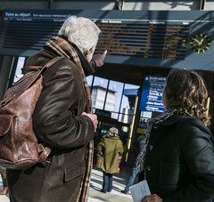 Voyageurs en gare devant affichage des trains au départ